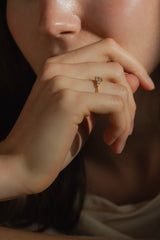 Ring DAWN von JUVELAN in Gelbgold an der Hand getragen – ovaler Diamant mit Tropfen und Brillanten als Seitensteine, Hand vor dem Mund