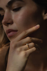 Ring ECLIPSE Rund von JUVELAN in Gelbgold an der Hand getragen – runder Brillant mit seitlichen Diamanten in niedriger Fassung, Hand an der Wange