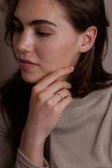 Ring EMBER Rund in Gelbgold am Finger, Hand am Kinn – zarter Solitär mit rundem Brillanten auf schlanker Ringschiene