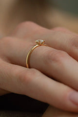 Ring SOL in Gelbgold am Finger im Profil – zarte runde Ringschiene mit Sechs-Krappen-Fassung und rundem Diamanten