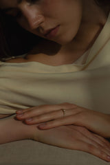 Ring TIDE | Trilogy von JUVELAN in Gelbgold an der Hand getragen – drei Diamanten auf schmaler Ringschiene, ruhende Hand auf cremefarbenem Stoff