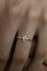 Ring VEGA von JUVELAN in Gelbgold am Finger getragen – Diamant im Tropfenschliff in hoher Krappenfassung auf schlanker, flacher Ringschiene
